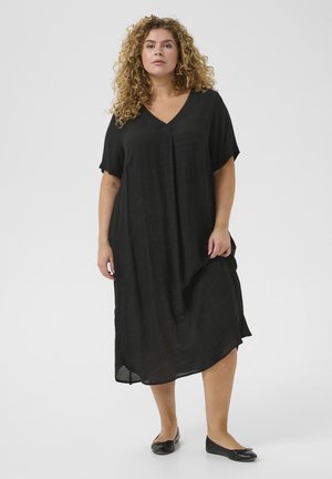 Zwarte, lichte jurk met korte mouwen, v-hals en een ontspannen fit, met een textuurstof en een asymmetrische zoom. Gepaard met zwarte flats.