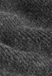 Gray wool fabric with a ribbed texture, showcasing softness and a slightly fuzzy appearance, arranged in gentle, flowing folds.