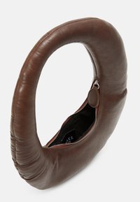 Bolso de piel marrón con un asa circular, que cuenta con una apertura con cremallera y un interior negro. El exterior tiene una textura suave y costuras mínimas.