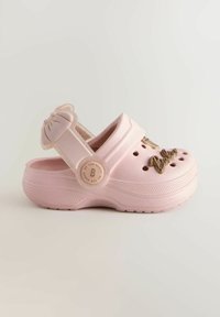 Roosa plastist wooden jalad, millel on lõikeventilatsiooniavad, lipsuaktsent rihmal ja dekoratiivne kiri külgedel.