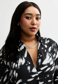 Zwart-witte gestreepte shirt met kraag en knopen, met een zachte textuur. Draag het met een zilveren ronde ketting.