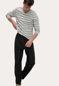 Camicia a maniche lunghe grigia a righe con accenti neri, abbinata a pantaloni neri con coulisse. Tessuto morbido, vestibilità rilassata, design casual.