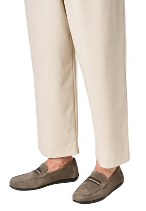 Pantaloni beige chiaro abbinati a mocassini taupe in suede con fasce elastiche a strisce e suole nere.