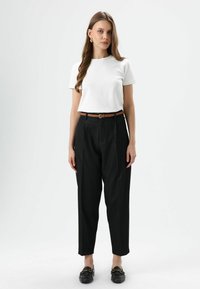 Witte korte mouwen T-shirt, hooggetailleerde zwarte broek met plooien, bruine gevlochten riem, zwarte loafers met gouden accenten. Eenvoudige, op maat gemaakte look.