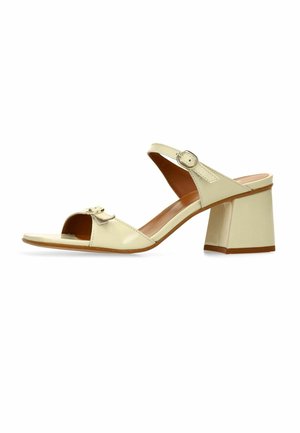 Sandale beige à bout ouvert avec un large talon bloc, une bride à la cheville avec une boucle argentée et une boucle décorative sur la bride avant.