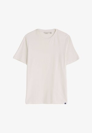 Biele tričko s krátkym rukávom vyrobené z mäkkej tkaniny. Obsahuje klasický okrúhly výstrih a malú námornícku nášivku na spodnom leme.