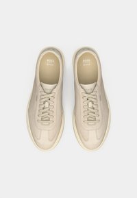 Pair of beige BOSS sneakers with laces, labeled Ortholite insoles, displayed from top view on a white background.