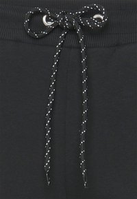 Svarta joggingsbyxor med en ribbad midja, en vävd dragsko med silvrig detalj och en slät textur.