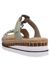 Sandale en suède vert avec une semelle intermédiaire en liège, une base à motifs et une sangle ajustable. Caractéristiques des accents tissés, une semelle extérieure en caoutchouc blanche et des détails texturés.