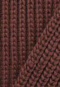 Teksturowana dzianina w głębokim burgundzie z wyraźnymi plecionymi wzorami, charakteryzująca się miękką, grubą nicią i ciepłym, przyjaznym wyglądem.