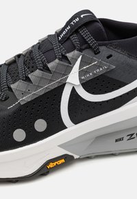 Black trail running shoe featuring a mesh upper with grey accents, perforated detailing, a white Nike logo, and a Vibram sole.