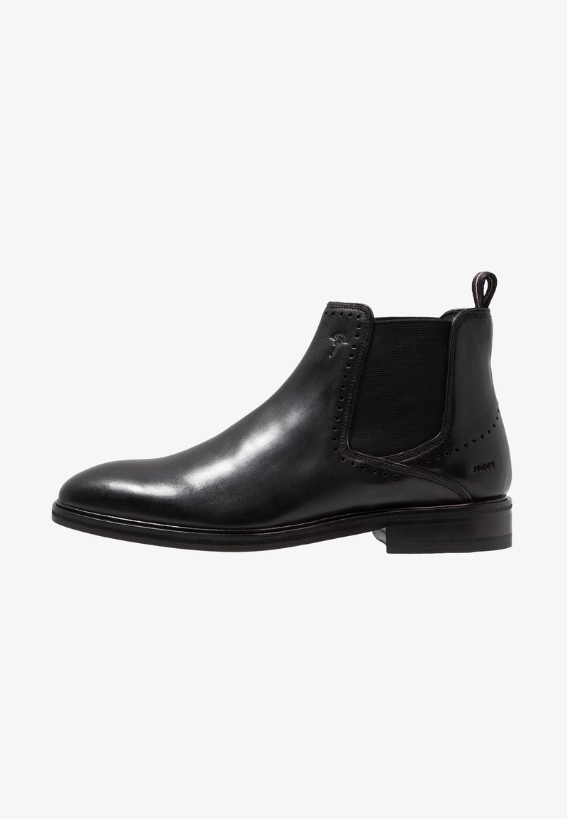 Bottine Chelsea en cuir noir avec panneau latéral élastique, petit talon, languette à l’arrière et petites perforations décoratives près de la cheville.
