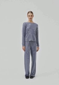 Loungewear set in light purple with a shiny, sequined texture. Long-sleeve top and matching wide-leg pants. Simple, relaxed fit.