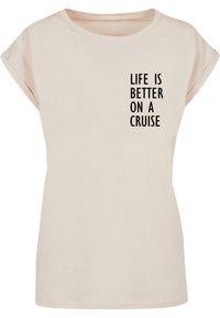 Helles beiges T-Shirt mit kurzen Ärmeln aus weichem Stoff, auf dem in schwarzer Schrift "LIFE IS BETTER ON A CRUISE" auf der Vorderseite steht.