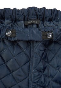 Bentiță din țesătură matlasată de culoare bleumarin, cu elastic și închidere ajustabilă cu capse, având eticheta "mikk-line." Textură netedă și model în formă de diamant.