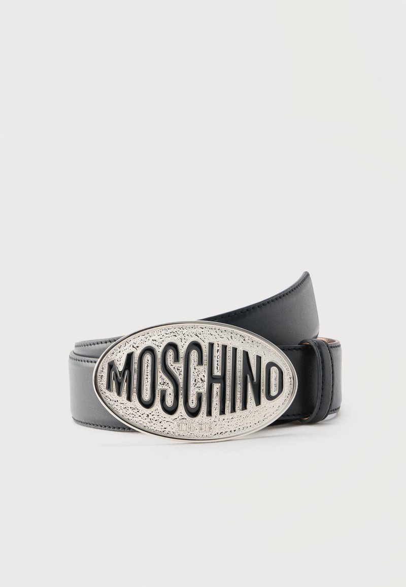 Ceinture en cuir noir avec une grande boucle ovale en argent ornée du texte "MOSCHINO" en relief, avec des lettres noires en gras.