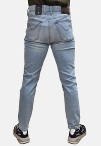 Jeans in denim azzurro chiaro con una vestibilità slim, caratterizzati da due tasche posteriori, cuciture sottili e etichette attaccate alla vita.