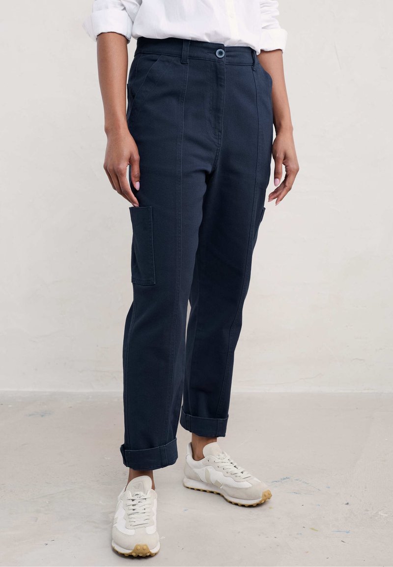 Meriininsininen cargo-housut suoran istuvuudella, joissa on sivutaskut ja käärityt lahkeet, valmistettu kestävistä kankaista, joissa on sileä pinta.