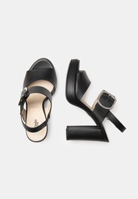 Black high-heeled sandals with a smooth leather finish, wide cross straps, ankle buckle, and a block heel. Light beige interior lining.