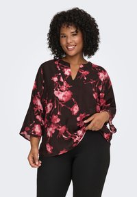 Black blouse with red floral pattern, 3/4 sleeves, V-neckline, lightweight fabric, and curved hem. Worn with black pants.