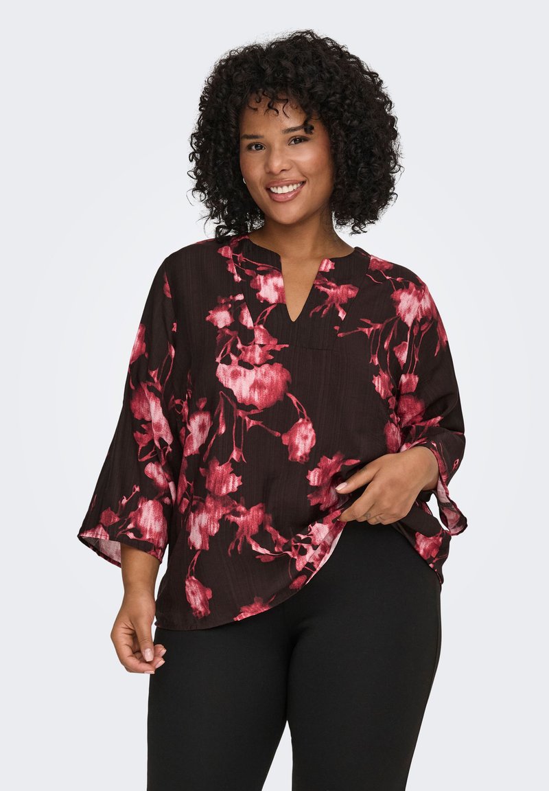 Black blouse with red floral pattern, 3/4 sleeves, V-neckline, lightweight fabric, and curved hem. Worn with black pants.