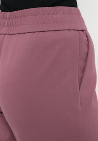 Lyserøde joggers med elastisk talje, sidelommer, glat tekstur og afslappet pasform, velegnede til afslappet brug og komfort.