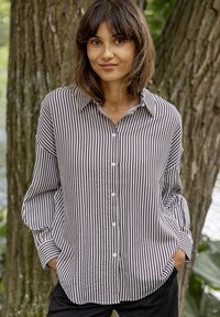 Striped button-up shirt in alternating dark and light tones; relaxed fit with long sleeves, a collar, and a rounded hem.