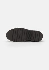 Suela de zapato de goma negra con surcos horizontales y una punta lisa y redondeada. Presenta un patrón texturizado para mejorar el agarre y la estabilidad.