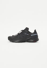 Chaussure de trail running noire avec une tige texturée, des lacets élastiques et une semelle extérieure Contagrip. Présente un ajustement serré et un pare-chocs protecteur.