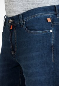 Dark denim jeans with orange accent on the waistband, silver button closure, and contrasting stitching, featuring a classic five-pocket design.