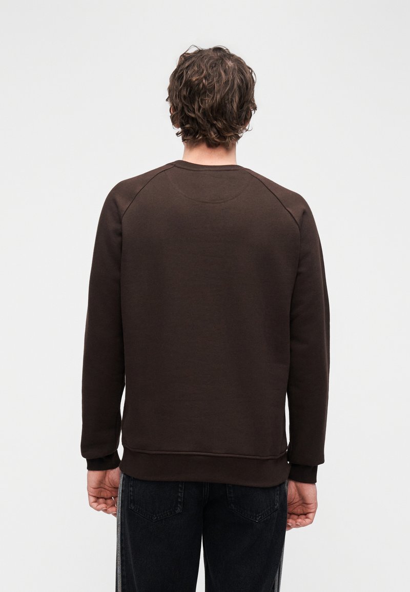 Brun sweatshirt av mjukt tyg, med rund hals och ribbade muddar. Mjuk textur, inga synliga mönster eller detaljer.