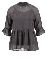 Haut peplum noir avec un motif texturé et ondulé, un col smocké et des manches 3/4 à volants. Fabriqué en tissu léger et transparent.