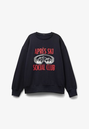 Granatowy sweatshirt z długimi rękawami, ściągaczami przy mankietach i u dołu. Zawiera biało-czerwony nadruk z napisem "Après Ski" oraz wzorem gogli narciarskich.