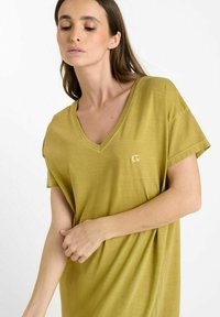 Olijfgroene V-hals t-shirt van zacht materiaal, met korte mouwen en een klein logo op de linkerkant van de borst. Lichtgewicht en relaxed fit.