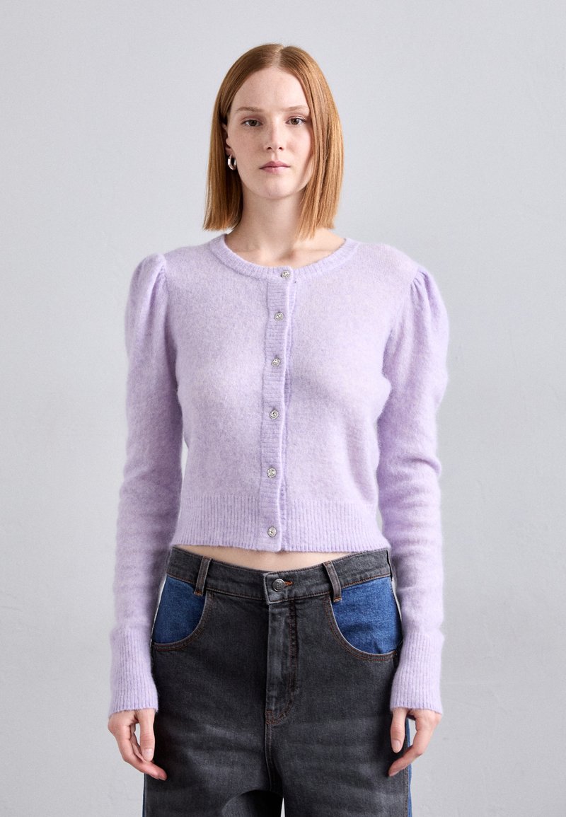 Fialový skrátený cardigan vyrobený z mäkkého, nadýchaného materiálu. Má vypuklé rukávy, rebrovaný spodný okraj a uzatváranie na šesť gombíkov s ozdobnými gombíkmi.