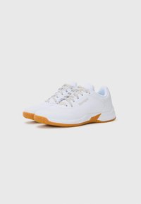 Chaussures de sport blanches avec un dessus en maille texturée, bout rond et semelle en caoutchouc beige clair. Elles disposent de lacets beiges et d'un accent de logo sur le côté.