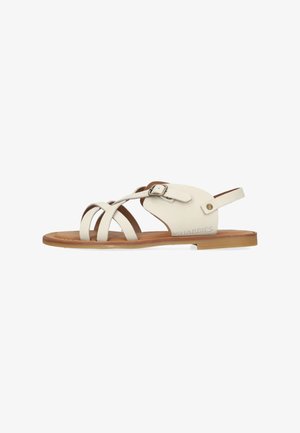 Sandale en cuir blanc avec design à bretelles croisées et boucle réglable à la cheville. Semelle marron clair avec un marquage subtil sur le côté. Profil plat.