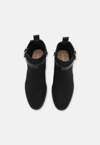 Černé kotníkové boty z kvalitního semiše, s lesklým páskem s krokodýlím vzorem, zaoblenou špičkou a dekoračním páskem s kovovými detaily.