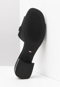Scarpa di pelle nera con suola in gomma testurizzata, punta quadrata e tacco robusto. L'interno presenta la dicitura "Made in Italy" e il logo del marchio.