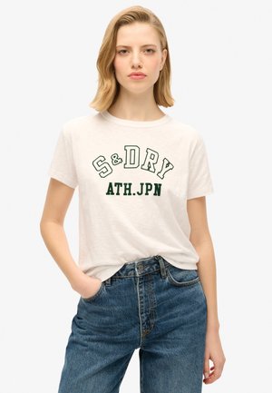 Cremefarvet bomulds T-shirt med "S&D" og "ATH.JPN" i grønne bogstaver, korte ærmer og rund halsudskæring, parret med høj talje blå jeans.