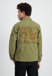 Chaqueta verde oliva con cuello mao, que presenta un gran diseño de dragón colorido y una bandera en la parte posterior; dos bolsillos frontales y puños con botones.