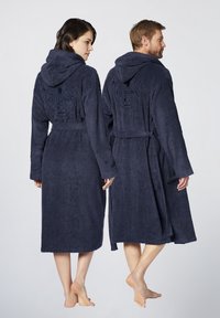 Navy-blue Kapuzenbademäntel aus Frottee mit einem Gürtel und einem gestickten Logo auf dem Rücken, gezeigt von zwei Models von hinten getragen.