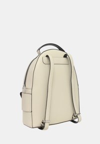 Mochila de cuero crema con acentos negros, forma redondeada, doble correas para los hombros y un bolsillo lateral. Cierre de cremallera en la parte superior.