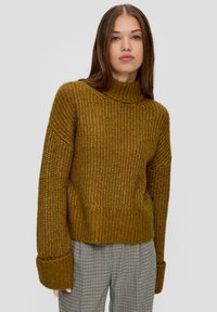 Senfgelbes Strickpullover mit hohem Kragen, lockerer Passform und breiten Bündchen; strukturierter Stoff mit geripptem Saum. Kombiniert mit karierter Hose.