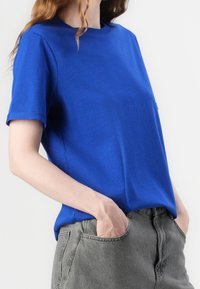 Royal blue short-sleeve t-shirt with a round neck and a relaxed fit, paired with gray denim shorts. Material appears soft and smooth.