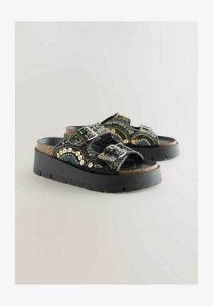 Schwarze Plattform-Sandalen mit Riemen, die über feine geometrische Perlenverzierungen und doppelte Schnallen verfügen, auf einem strukturierten Korkfußbett.