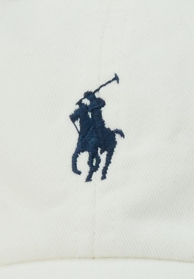 Vezen modri igralec polo na konju, ki maha z kladivom na belem blagu, centrirano blizu šiva.