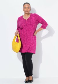 Rosa Tunika-Kleid mit Zebra-Muster, Rundhalsausschnitt und drei Viertel-Ärmeln, kombiniert mit schwarzen Leggings und einer gelben geflochtenen Handtasche.