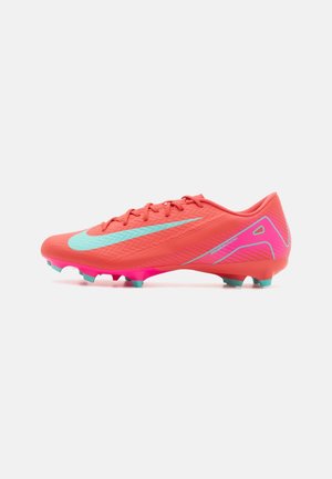 Botas de fútbol Nike en un vibrante color coral con acentos en aqua. Diseño elegante, parte superior texturizada y suela rosa con tacos azul claro para tracción.