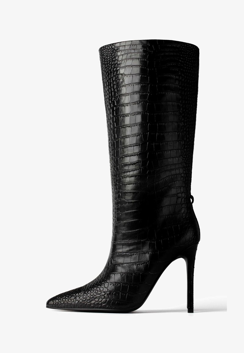 Fekete, térd fölé érő csizma, amely texturált műbőrből készült, krokodil mintázattal, hegyes orral és magas tűsarkúval.